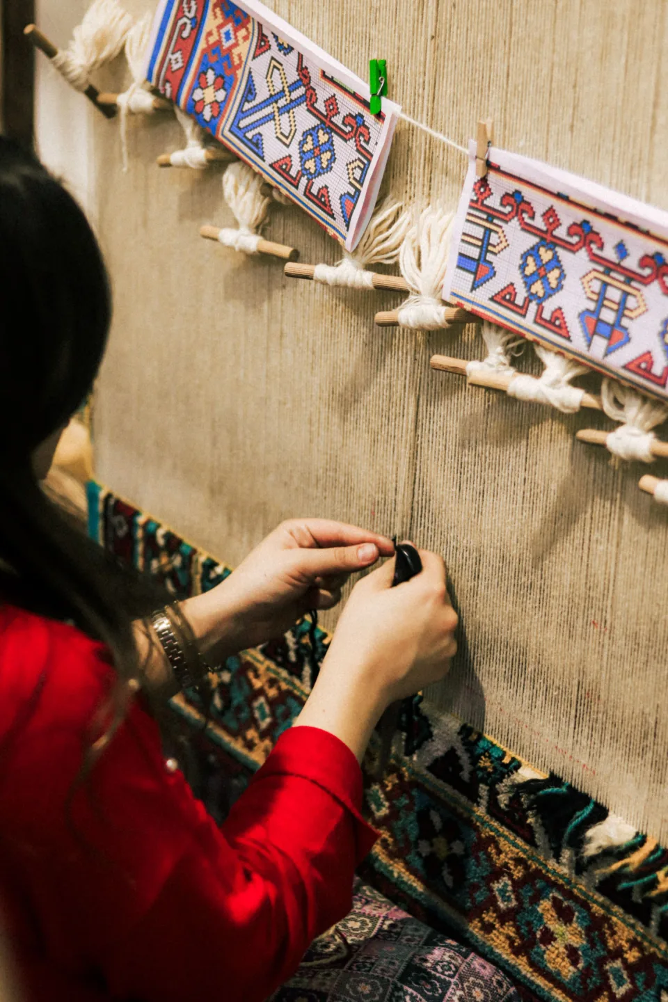 Hands tying knots on a loom